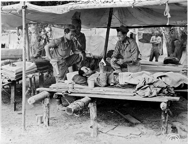 MIS soldiers interrogate wounded  Japanese prisoner.